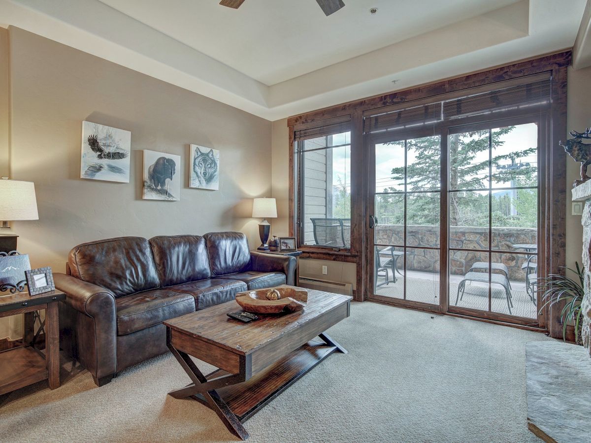 A cozy living room with a brown leather sofa, wooden coffee table, wall art, and large sliding doors to a patio.