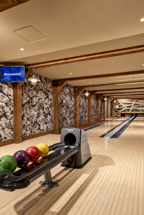Indoor bowling alley with a Brunswick video screen, wood lanes, and colorful bowling balls on the approach.
